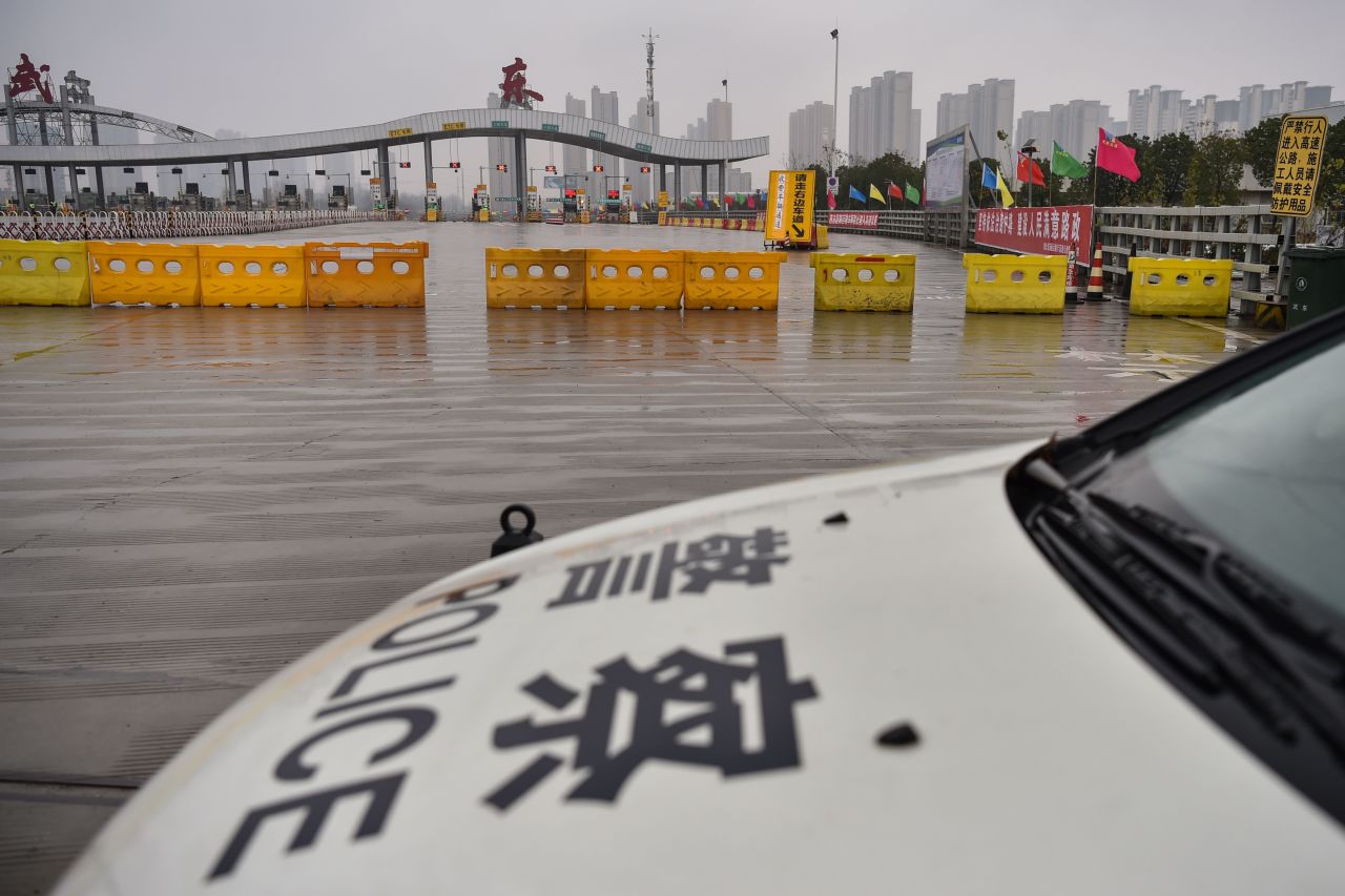 A police car is seen in front of one of the roads blocked by authorities to restrict people leaving Wuhan in China's central Hubei province on Saturday.