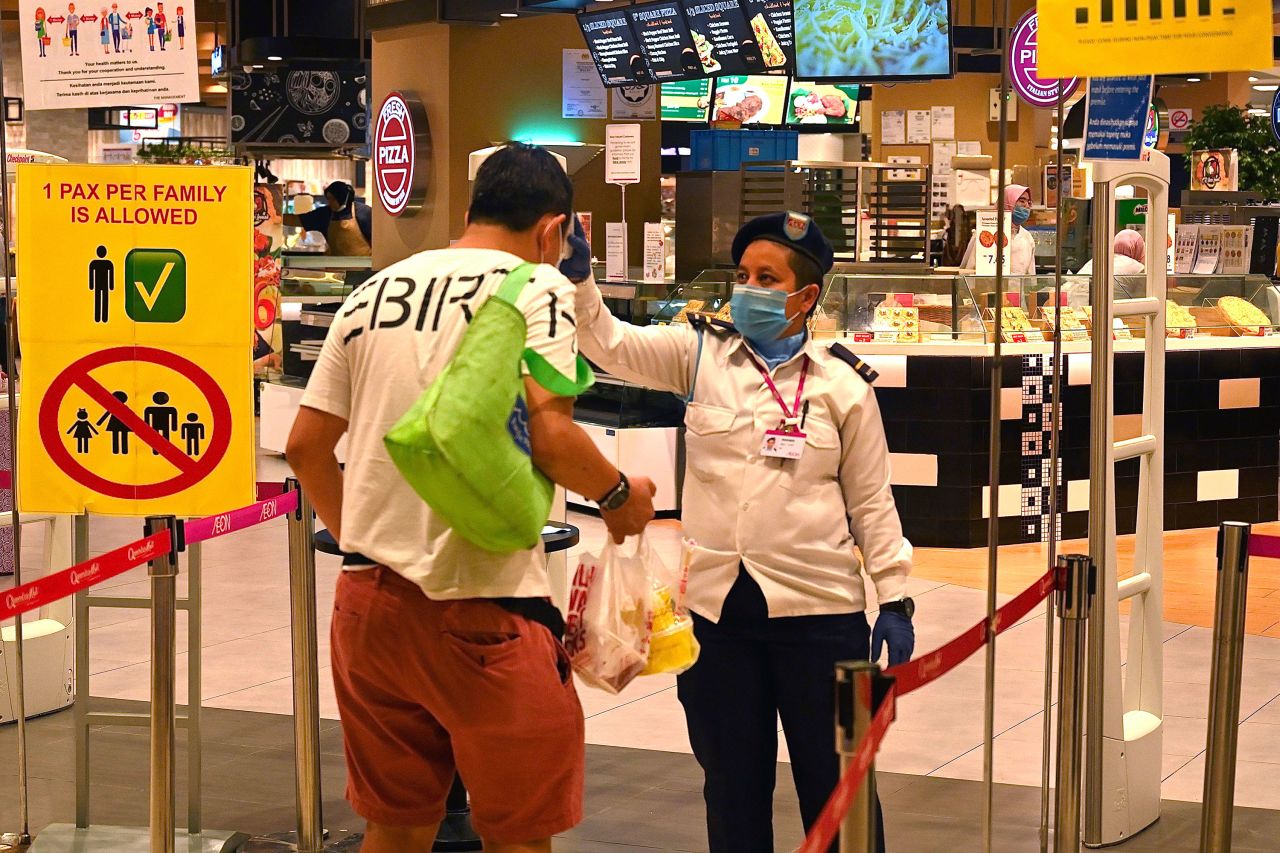 A security guard checks the temperature of a customer arriving at a supermarket in Penang, Malaysia on March 27. 