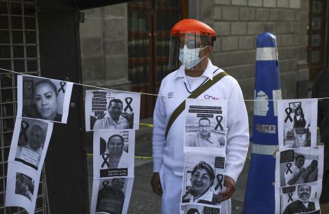 A hospital worker stands with images of colleagues who have died from Covid-19 during a protest in front of the National Palace in Mexico City on May 29. 