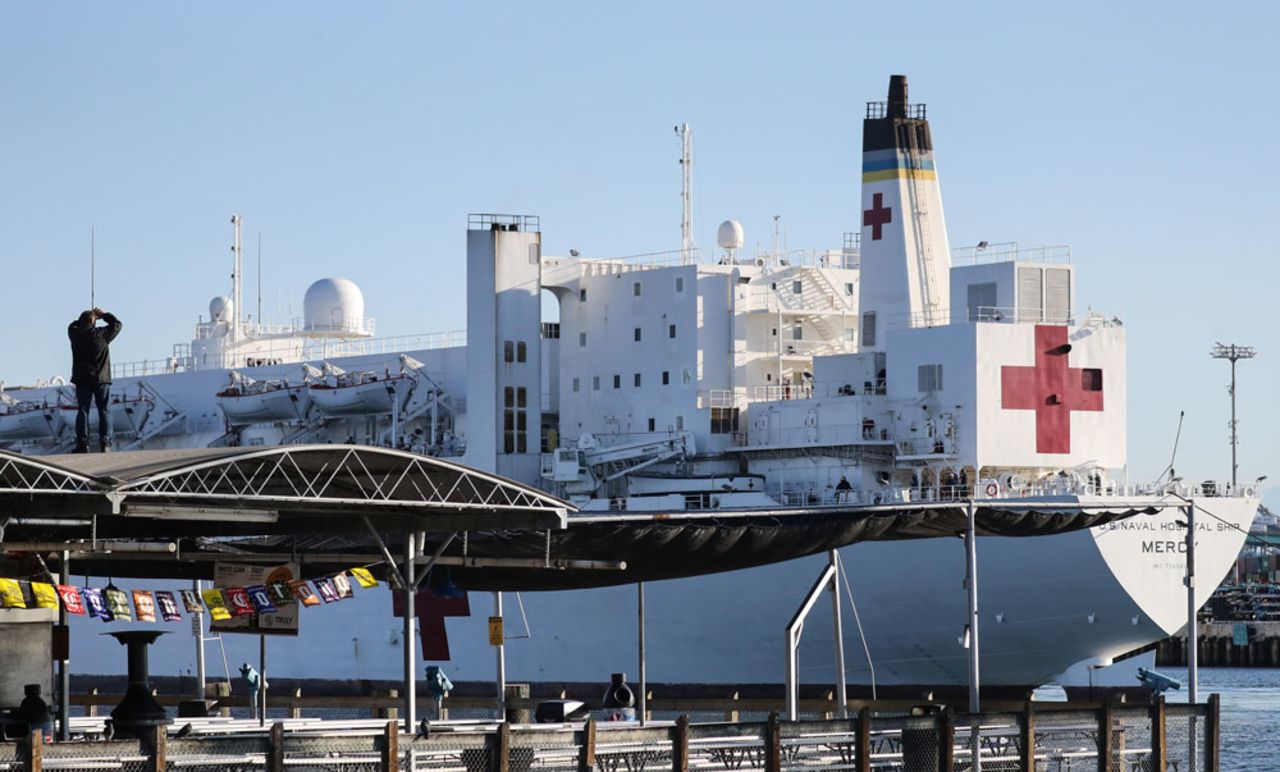 A man watches from a roof as the USNS Mercy Navy hospital ship arrives in the port of Los Angeles to assist with the coronavirus pandemic on March 27, 2020 in San Pedro, California. 