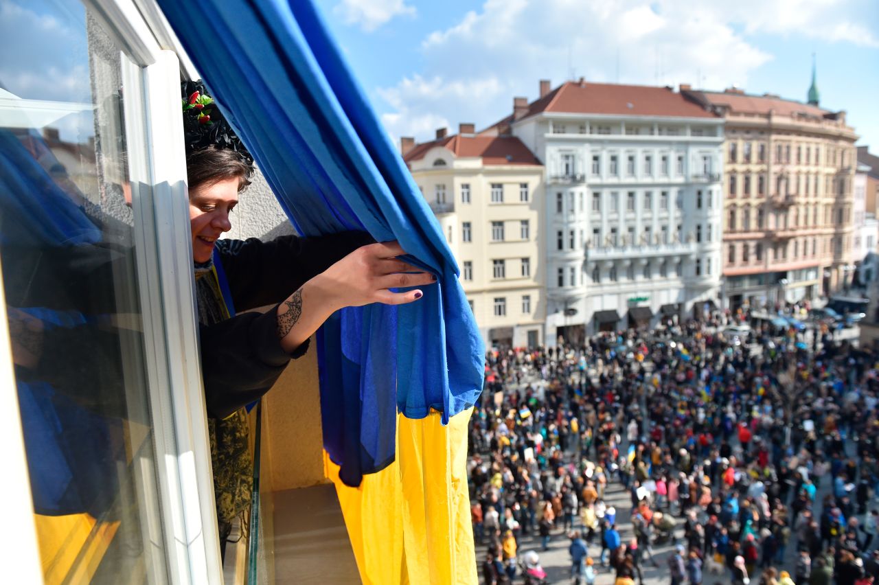 A woman hangs a flag from a window during a demonstration in support of Ukraine, on February 27, in Brno, Czech Republic. 