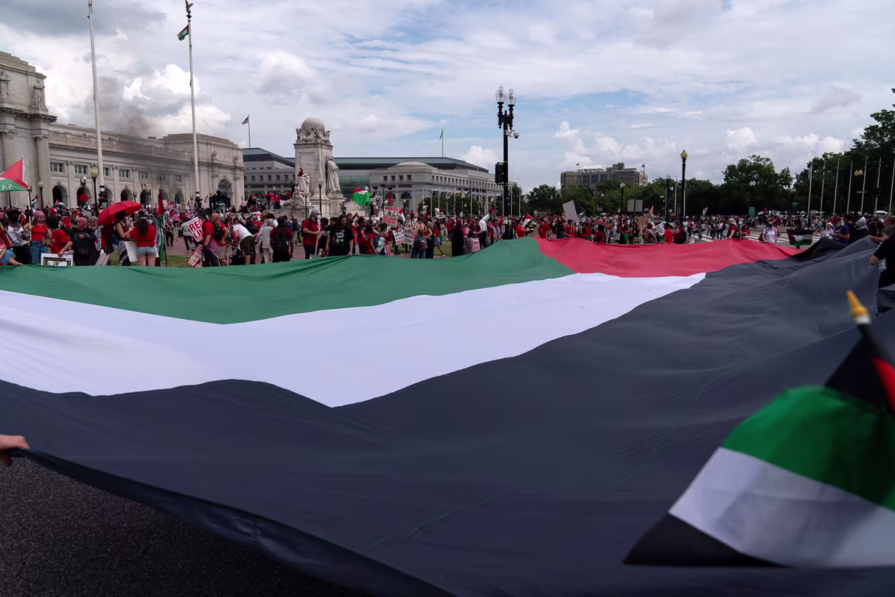Demonstrators carry a large Palestinian flag at Columbus Circle, in Washington, DC,  as they protest the visit of Israeli Prime Minister Benjamin Netanyahu.