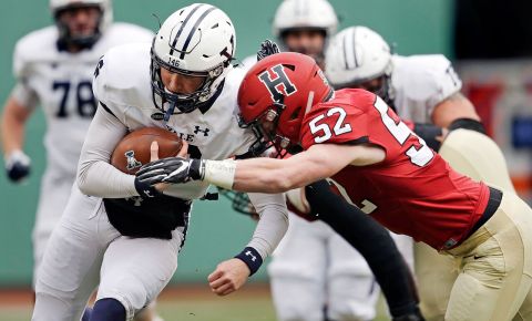 In this November 17, 2018 file photo, Yale quarterback Griffin O'Connor, left, tries to elude Harvard linebacker Cameron Kline (52) while scrambling for a gain during the first half of an NCAA college football game at Fenway Park in Boston.