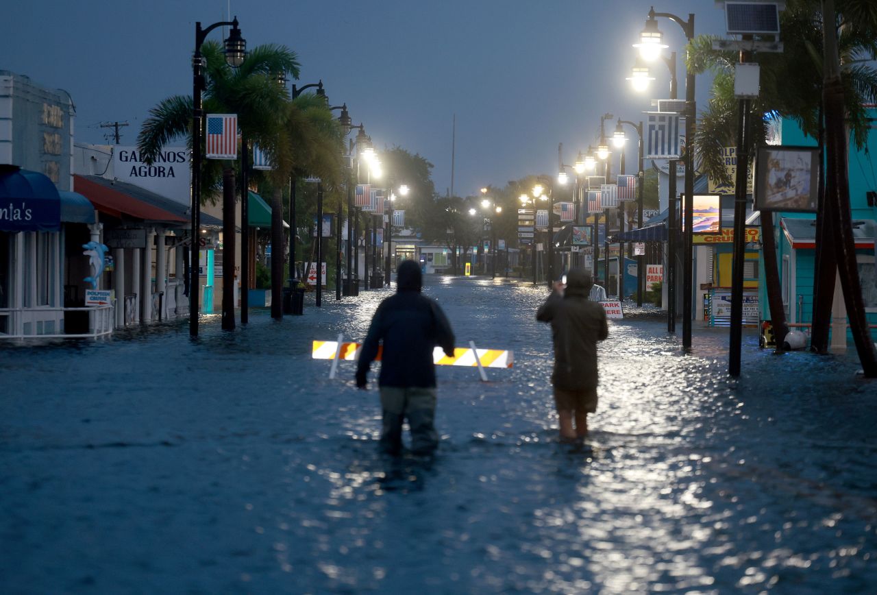 Reporters wade through flood waters as it inundates the downtown area of Tarpon Springs early Wednesday.