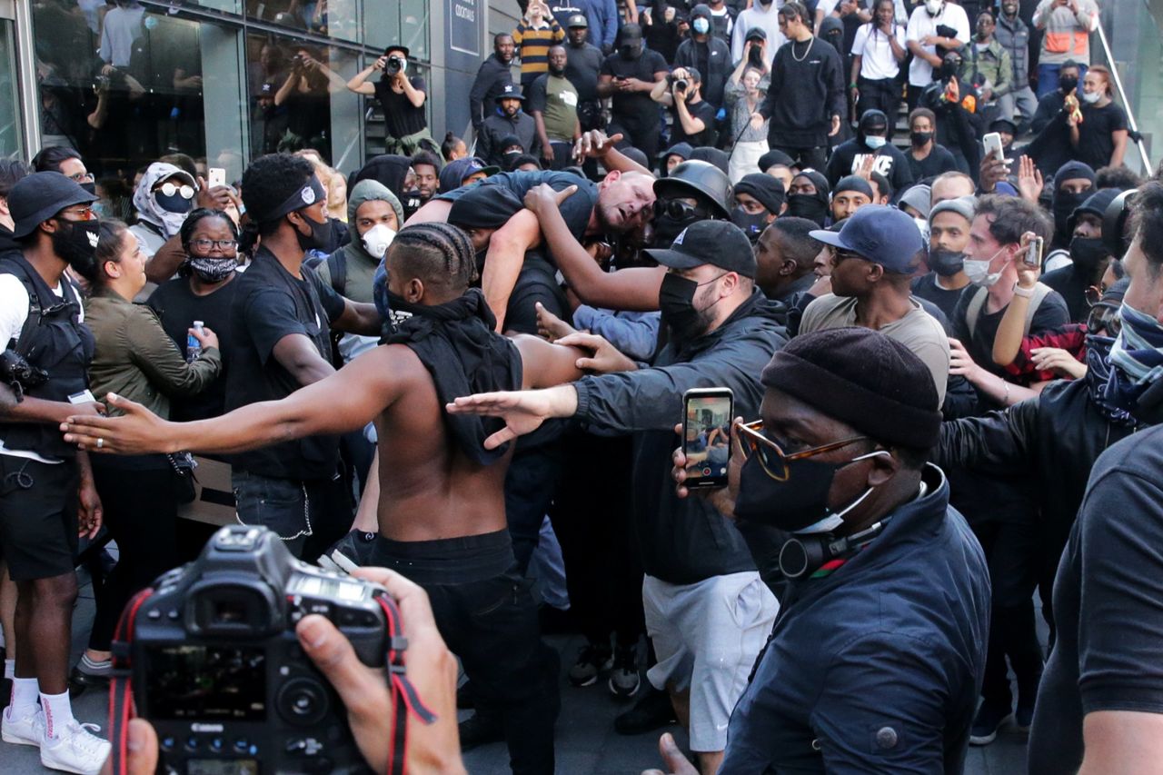 A group of men carry an injured man away after he was allegedly attacked by some of the crowd of protesters, as police try to intervene on the Southbank near Waterloo station in London on June 13, 2020.