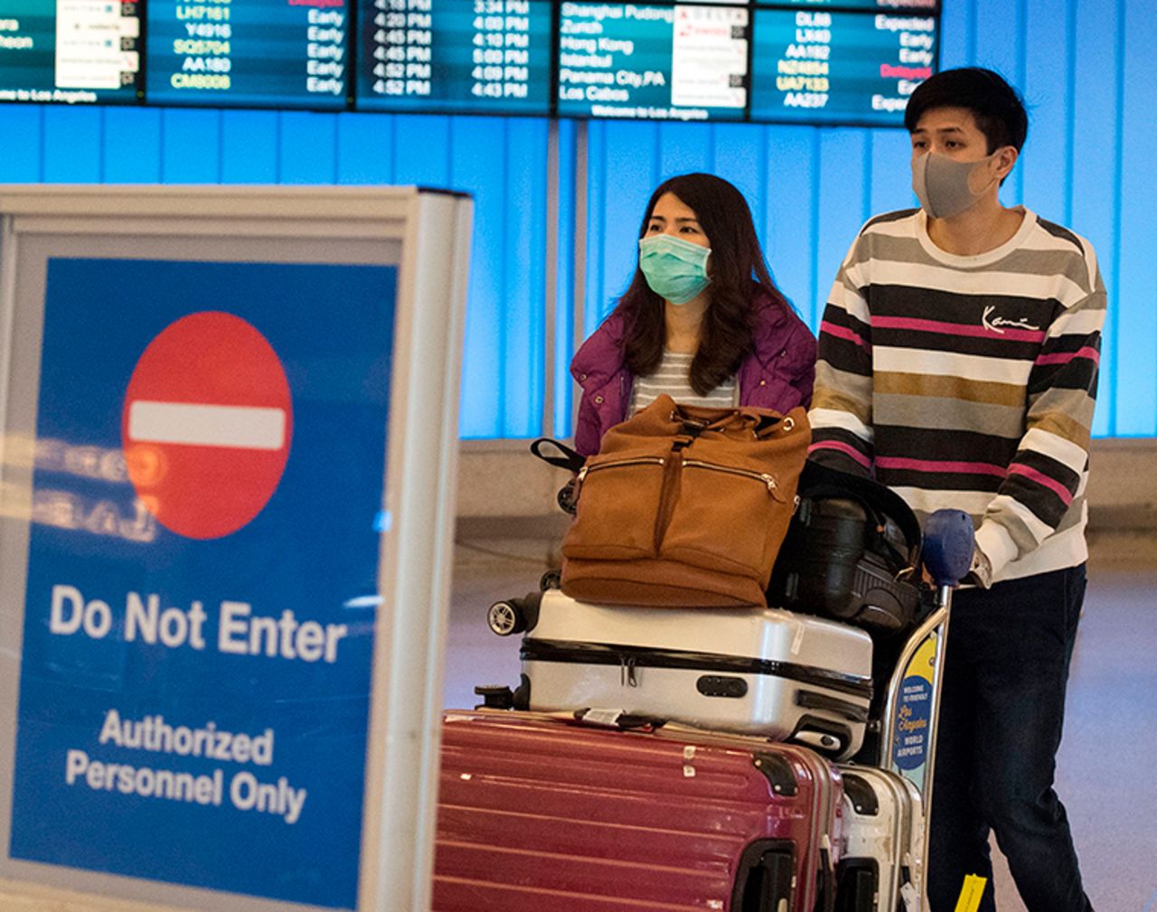 Passengers wear protective masks to protect against the spread of the coronavirus as they arrive at the Los Angeles International Airport  on January 22.