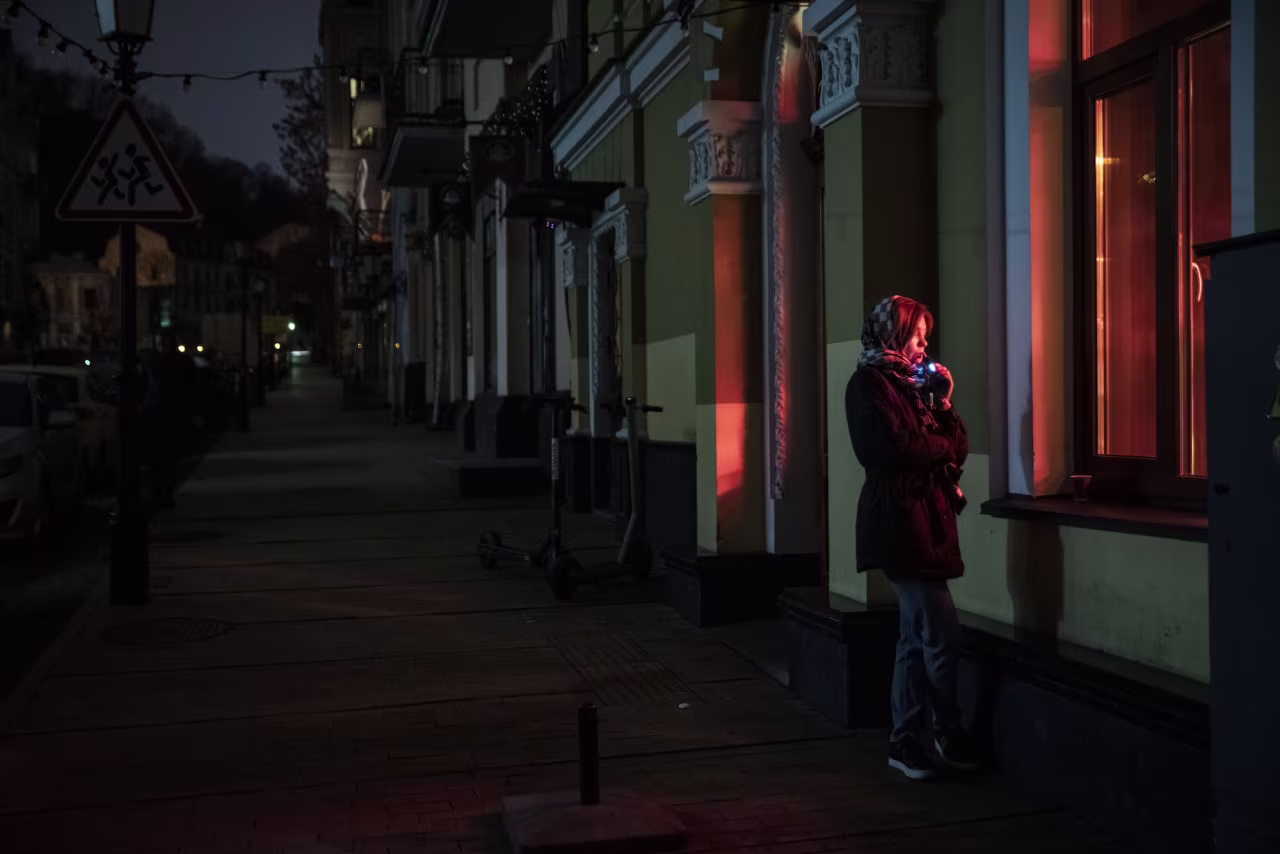 A woman stands outside a cafe on a dark street in Kyiv on Monday.