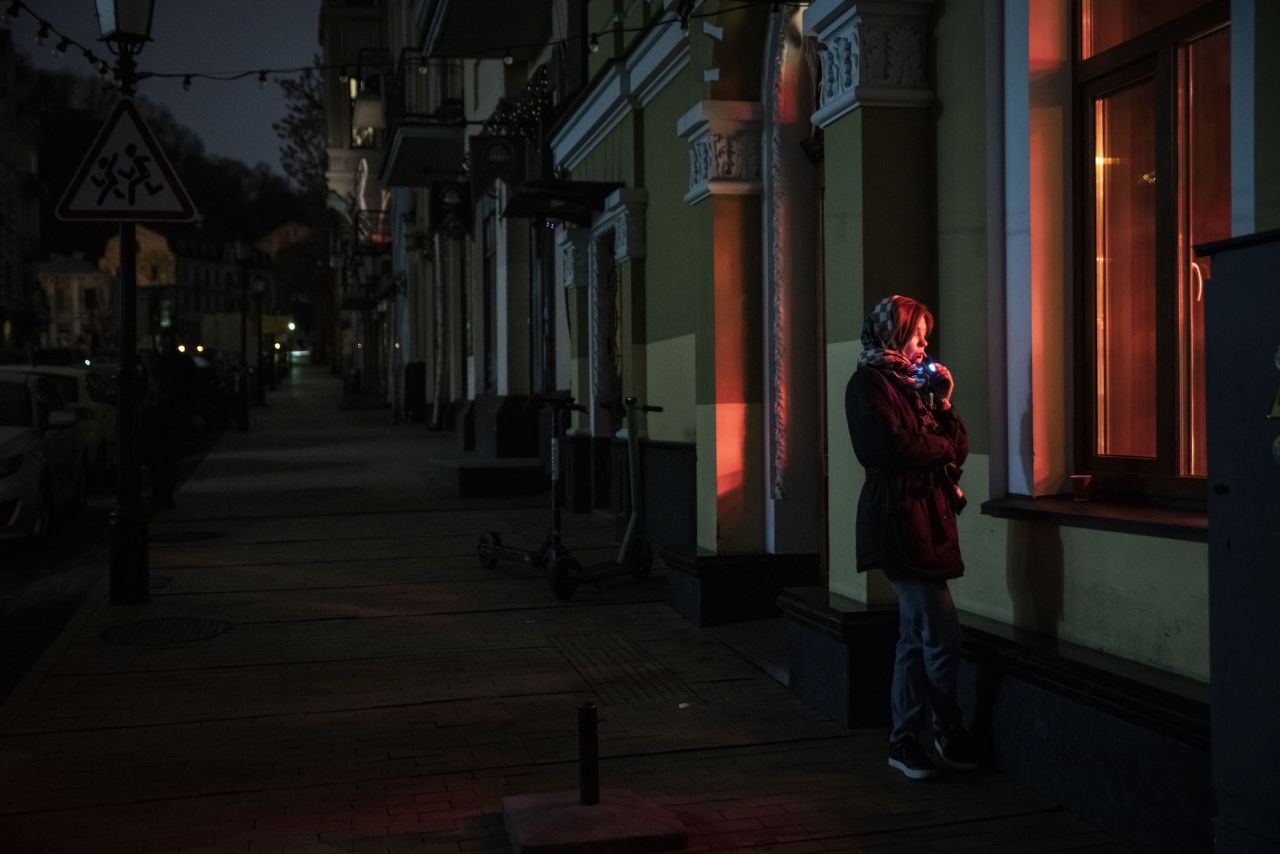 A woman stands outside a cafe on a dark street in Kyiv on Monday.