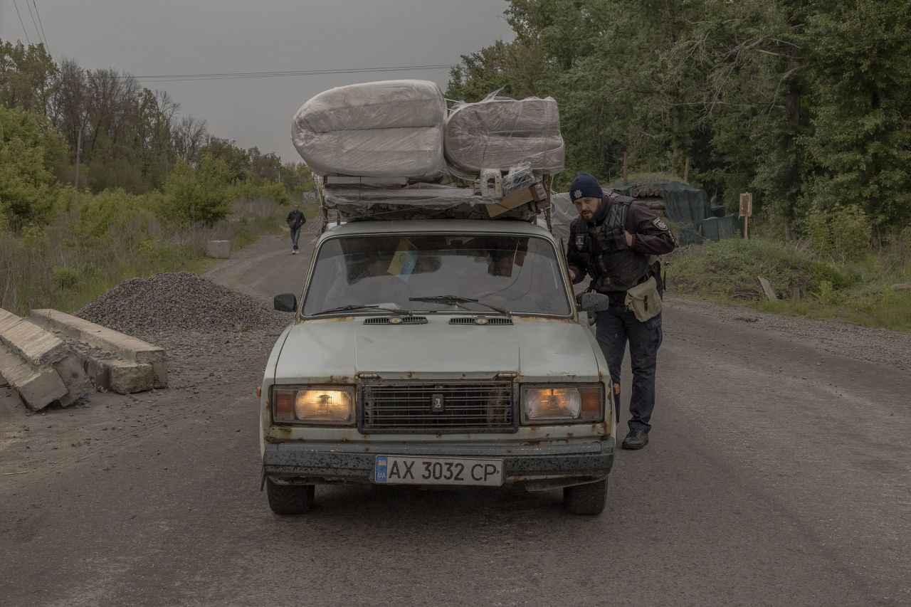 A policeman checks a car carrying people who have fled the village of Tsyrkuny, at a checkpoint outside Kharkiv, on May 13.