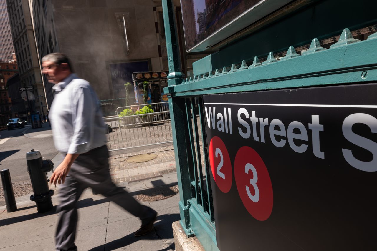 People walk along Wall Street outside of the New York Stock Exchange on August 5.