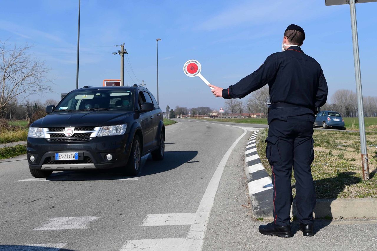 An Italian official stops a car at a police check-point near Castiglione d'Adda, southeast of Milan, on Monday.