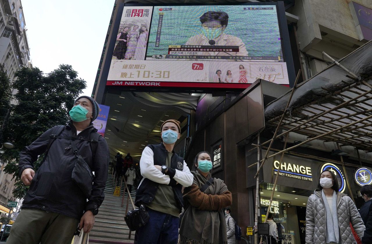 People stand in front of a TV screen broadcasting Hong Kong Chief Executive Carrie Lam speaking in Hong Kong.