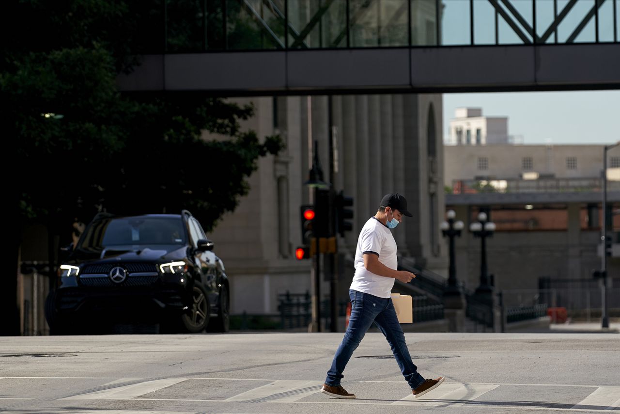 A pedestrian wearing a protective mask walks in downtown Dallas, Texas on Wednesday, May 27.