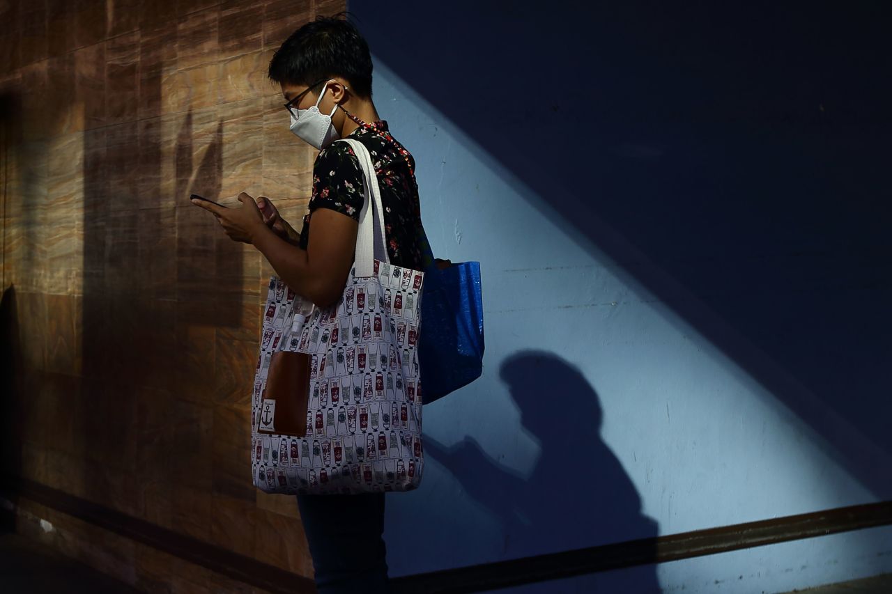 A woman wearing protective mask uses her mobile phone while waiting for a bus on January 13 in Singapore.