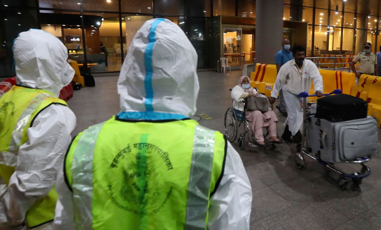 Indian municipal workers in personal protective equipment watch as passengers arrive from the United Kingdom, at Chhatrapati Shivaji Maharaj International Airport in Mumbai on December 22.