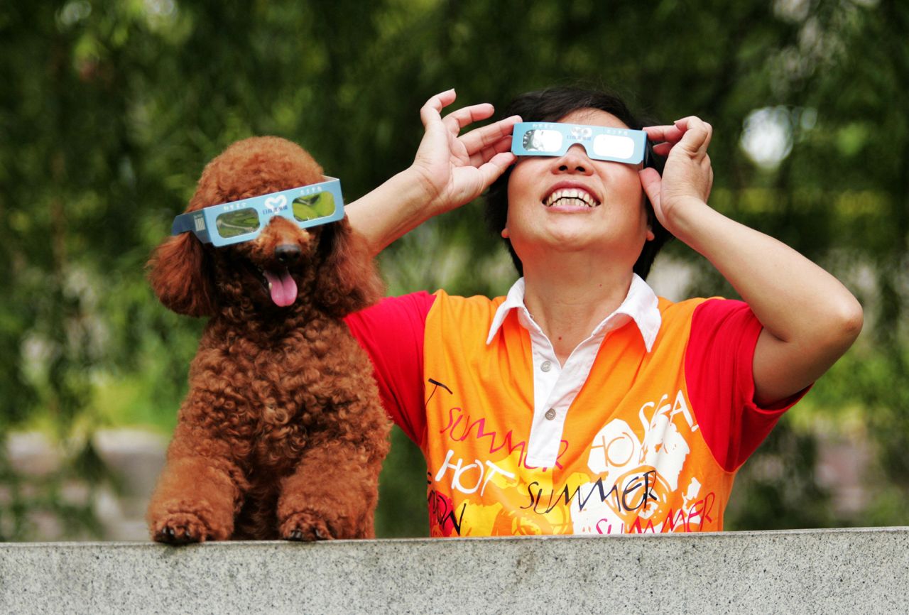 A woman observes the solar eclipse with her poodle in Hangzhou, China on July 22, 2009. 