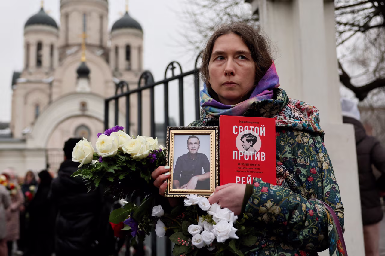 A person holds Navalny's portrait outside the church after the funeral service.