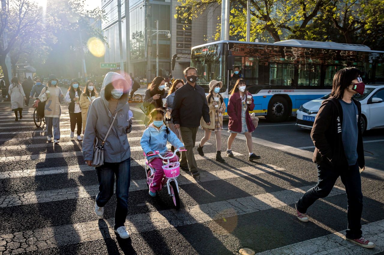 People wearing facemasks amid concerns over the COVID-19 coronavirus cross a street in Beijing on April 21. 