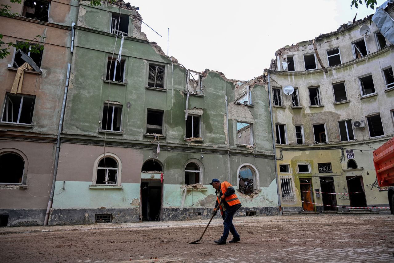 A communal worker sweeps outside an apartment building in the western Ukrainian city of Lviv, on July 7, a day after it was partially destroyed by a missile strike.