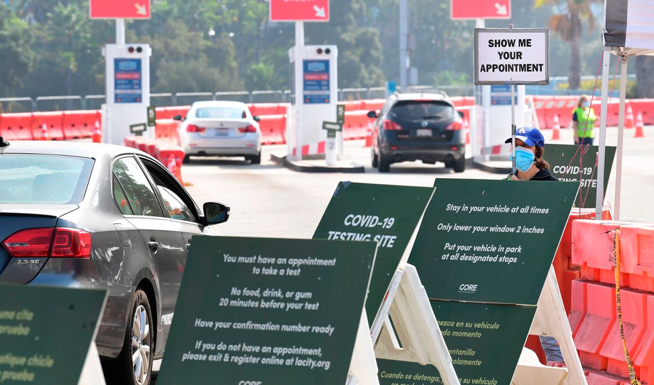 A volunteer wearing a face mask displays a sign checking for Covid-19 test appointments from motorists arriving at Dodger Stadium in Los Angeles, on October 8.