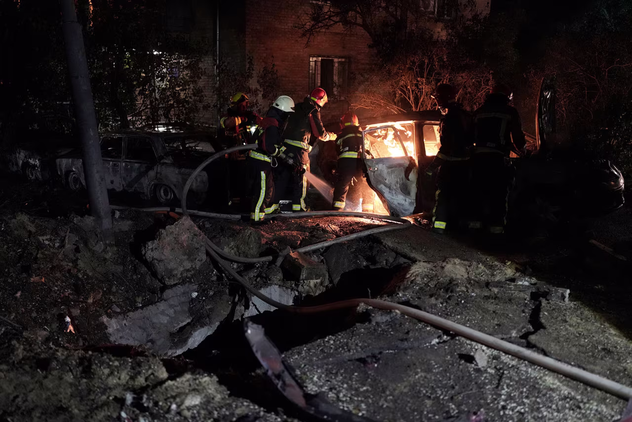 Emergency workers extinguish a fire in a parked car caused by falling debris from an aerial  attack in Kyiv, Ukraine, on Tuesday, May 30.
