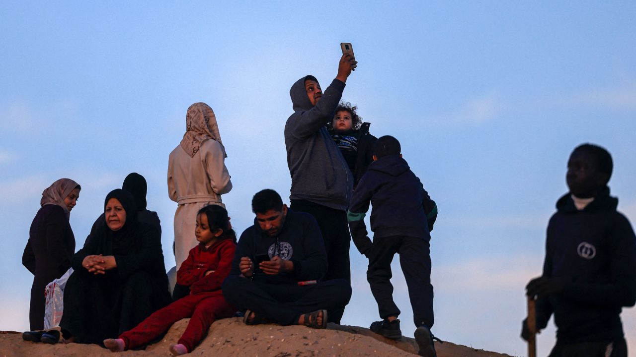 Displaced Palestinians try to get a cell phone signal on a hill in Rafah, Gaza, on Friday.