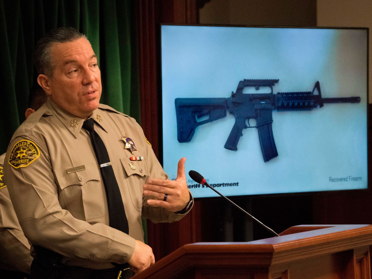 Los Angeles County Sheriff, Alex Villanueva, speaks beside an image of a seized semi-automatic weapon as he briefs the media after the arrest of a 13-year-old boy who allegedly threatened to carry out a shooting at Animo Mae Jemison Charter Middle School, in Los Angeles, California, on November 22, 2019.