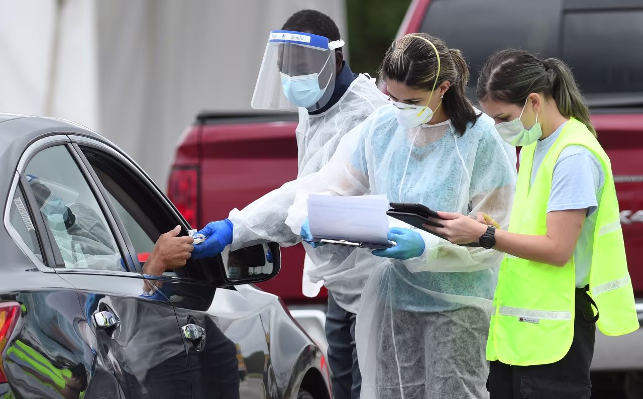 Health care workers greet people as they arrive at a temporary drive-through Covid-19 testing site in Orlando on October 1.