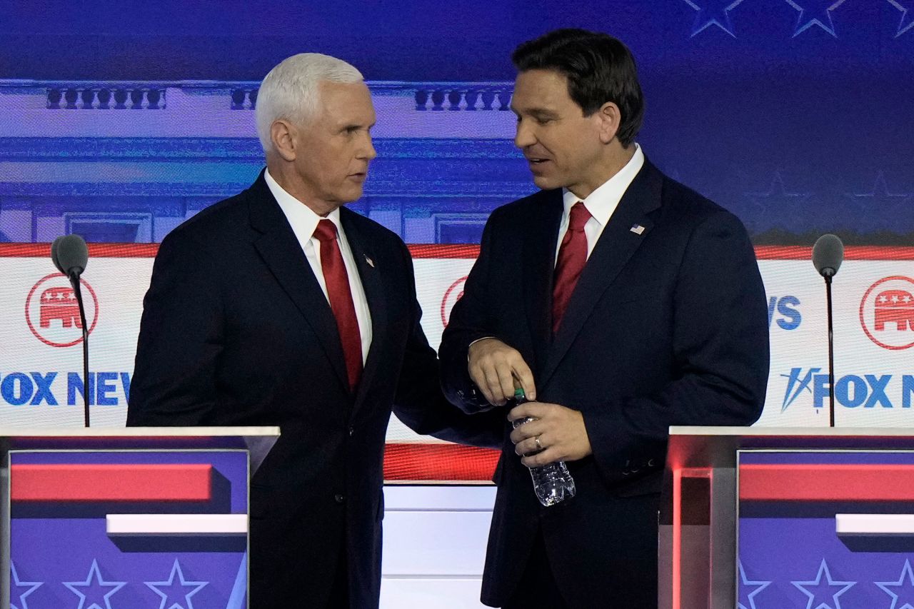 Former Vice President Mike Pence talks with Florida Gov. Ron DeSantis during a break at a Republican presidential primary debate hosted by FOX News Channel on Wednesday.