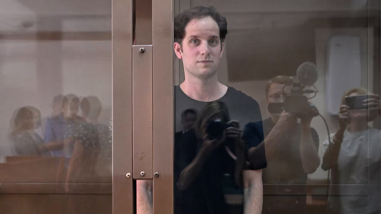 Journalist Evan Gershkovich stands inside a defendants' cage before a hearing in Moscow in June.