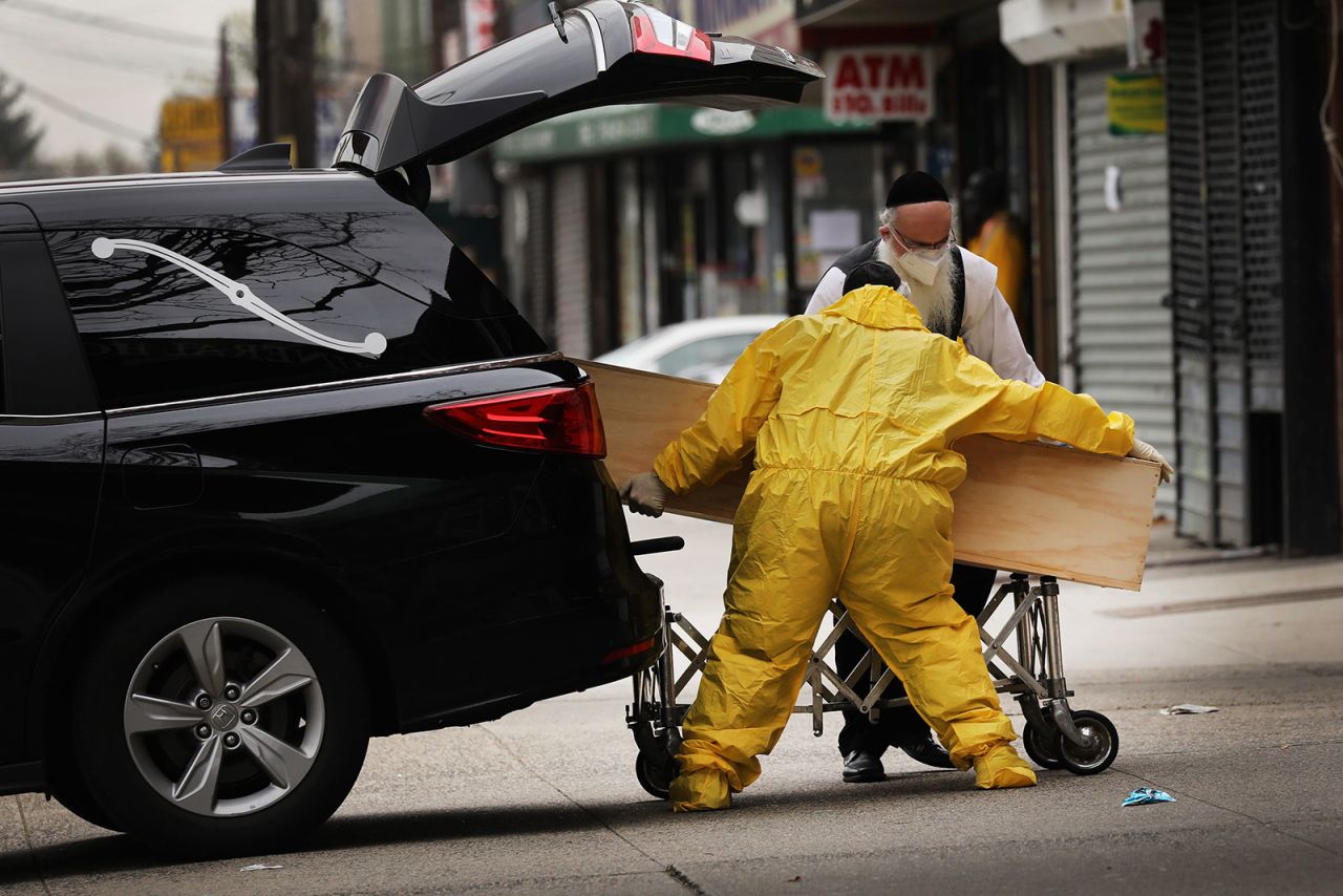 Men unload a wooden casket from a hearse at a funeral home in Brooklyn, New York, on April 5.