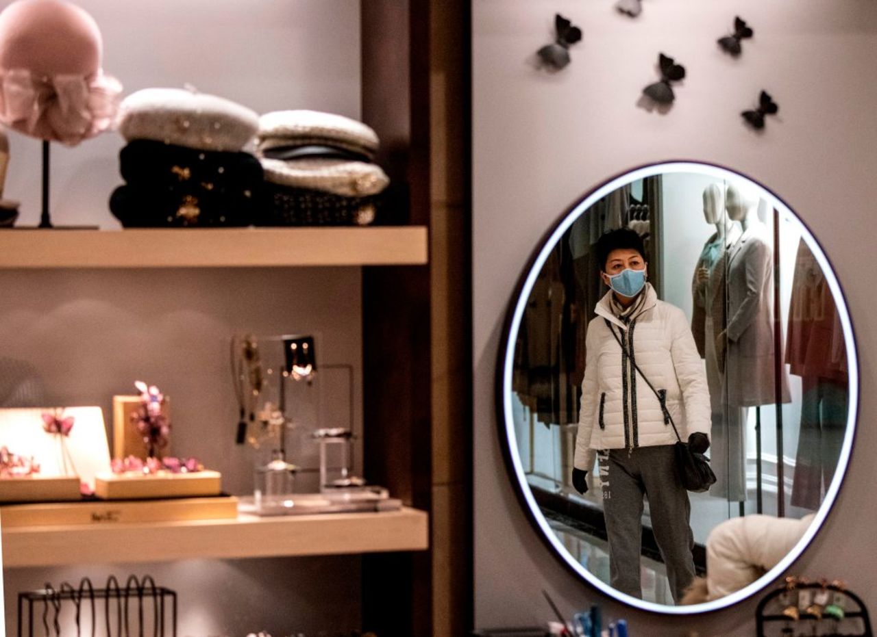 A woman wearing a protective face mask is reflected in a mirror as she walks inside a mall in Shanghai on February 8.