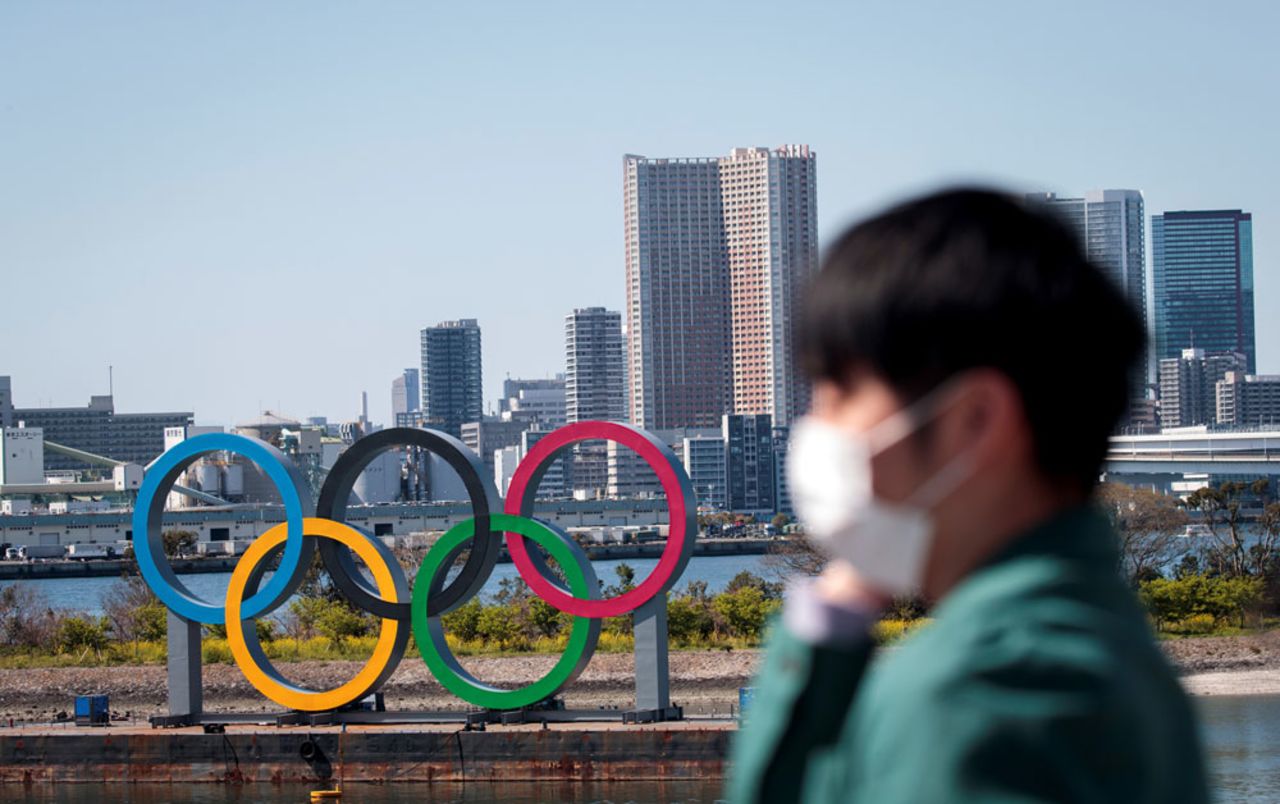 A man wearing a face mask stands before the Olympic rings from an observation point in Tokyo's Odaiba district on March 25.