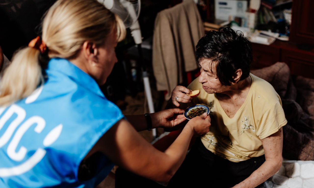 A JDC aid worker provides a taste of apples and honey to an elderly Jewish woman in the besieged city of Dnipro. The apples and honey were included in JDC's Rosh Hashanah food aid packages provided to thousands of poor Jewish seniors across Ukraine.