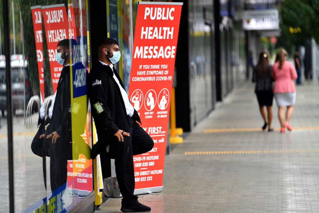 A security guard with a face mask stands outside a pharmacy in Sydney on March 27.