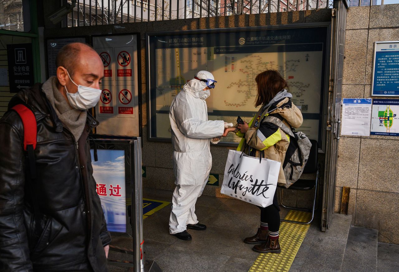 A Chinese worker is dressed in a protective suit as he takes the temperature of a woman at a subway station during the Chinese New Year and Spring Festival holiday on January 28 in Beijing.