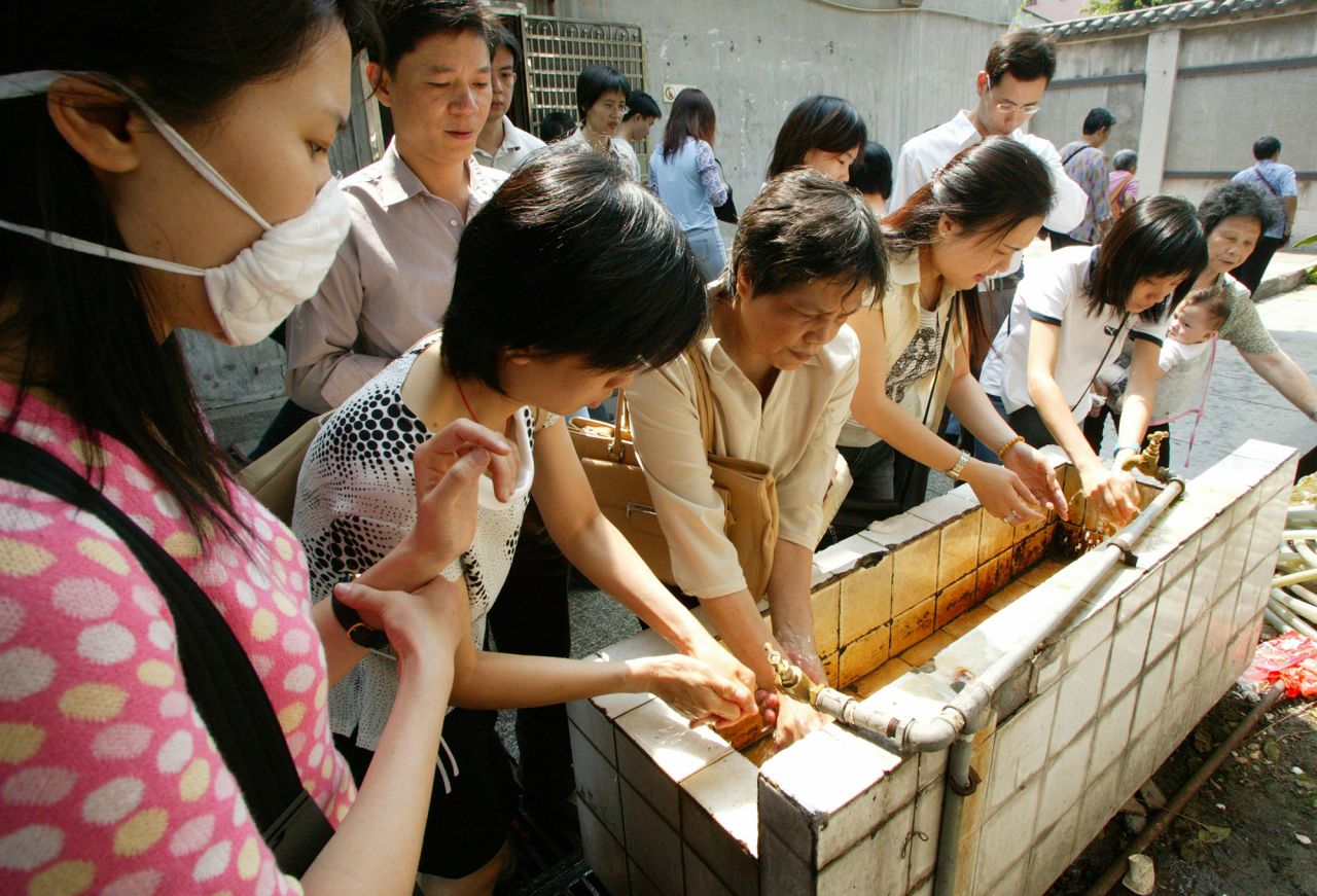 People wait in line to clean their hands on May 1, 2003 amid the SARS outbreak in the Guangdong province capital of Guangzhou, China.