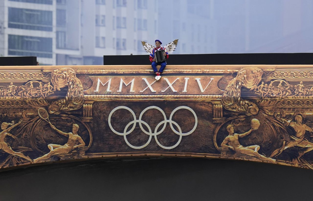 A performer sits on a bridge in Paris during the opening ceremony 