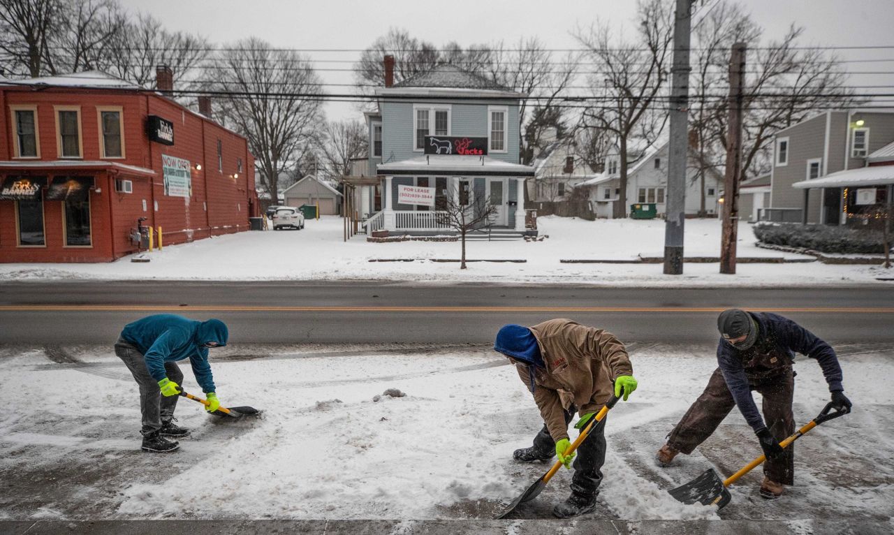 People shovel ice and snow from a winter storm in front of shops on Frankfort Avenue in Louisville, Kentucky, Monday February 15.