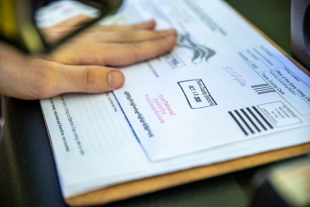 A poll worker stamps a voters ballot before dropping it into a secure box at a ballot drop off location on October 13, in Austin, Texas. 