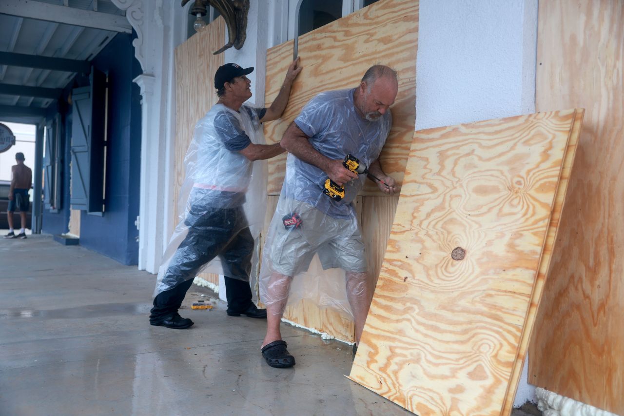 Tom Street, left, and Dan Norman place plywood over the windows of a business as they prepare for the possible arrival of Debby in Cedar Key, Florida, on August 4. 