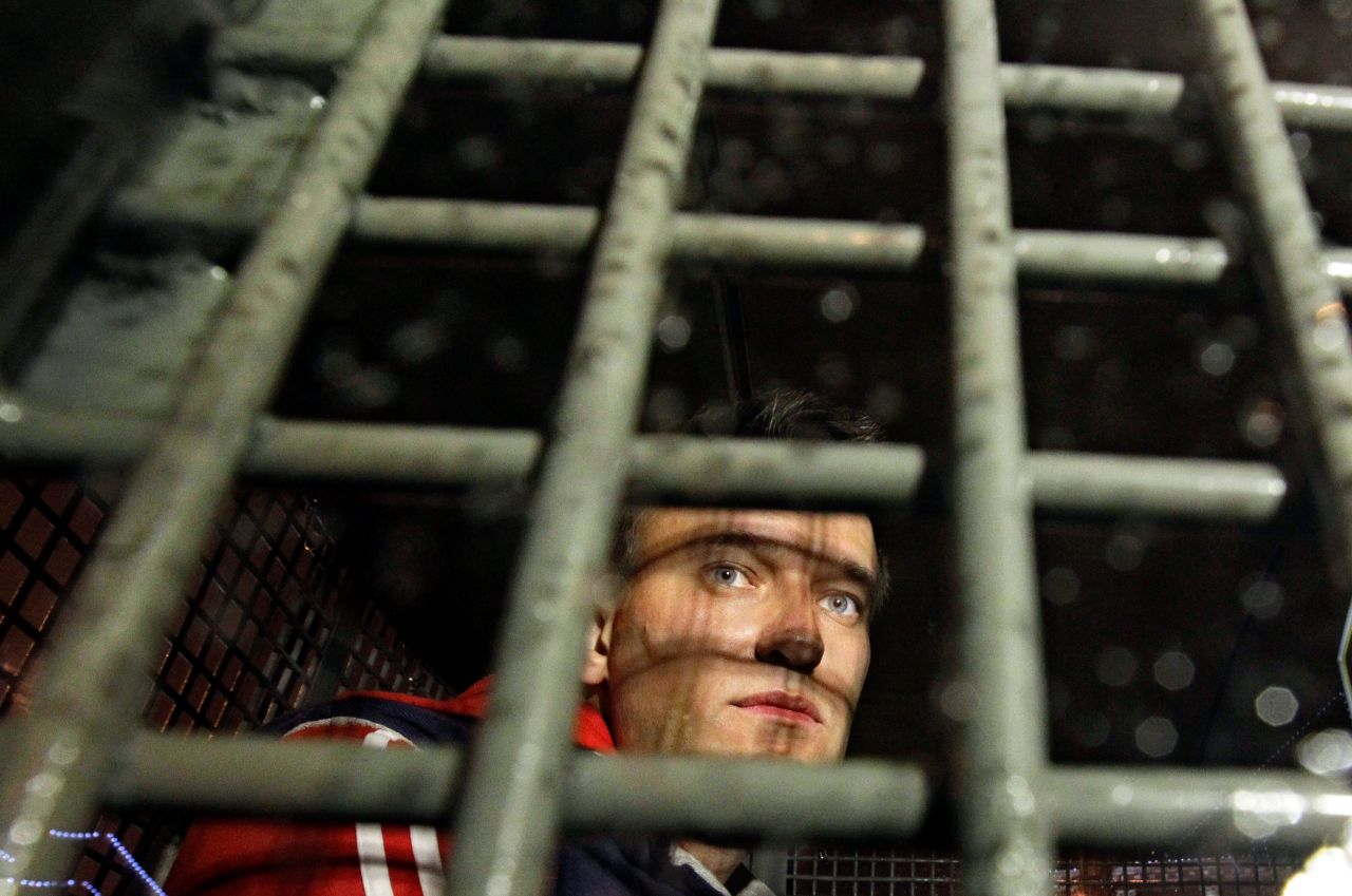 Alexey Navalny sits inside a police van after he was detained during protests in Moscow in 2012.