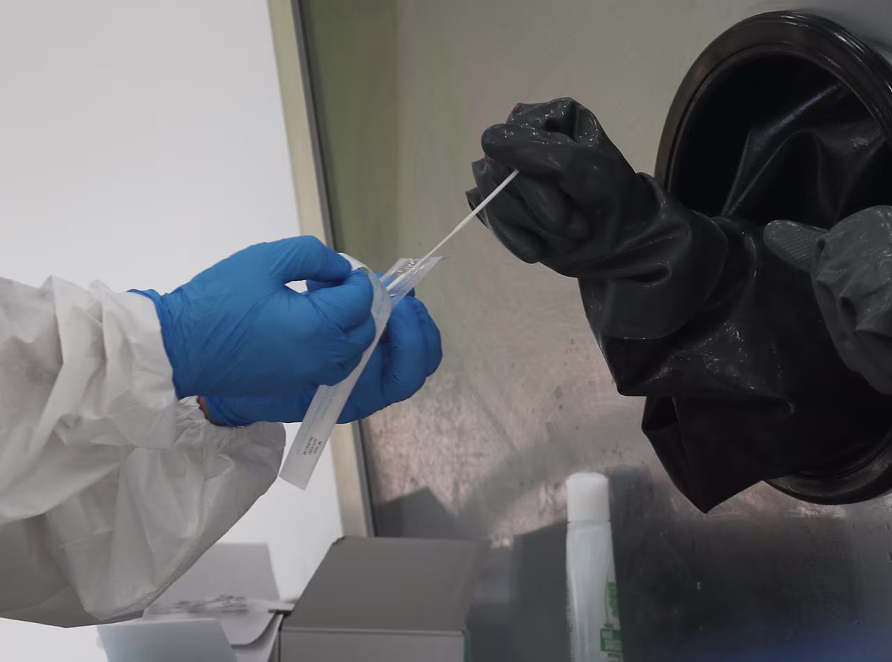A nurse receives a swab to test a person through a glass pane in the Aardvark Mobile Health’s Mobile Covid-19 Testing Truck on July 17, in Miami Beach, Florida. 