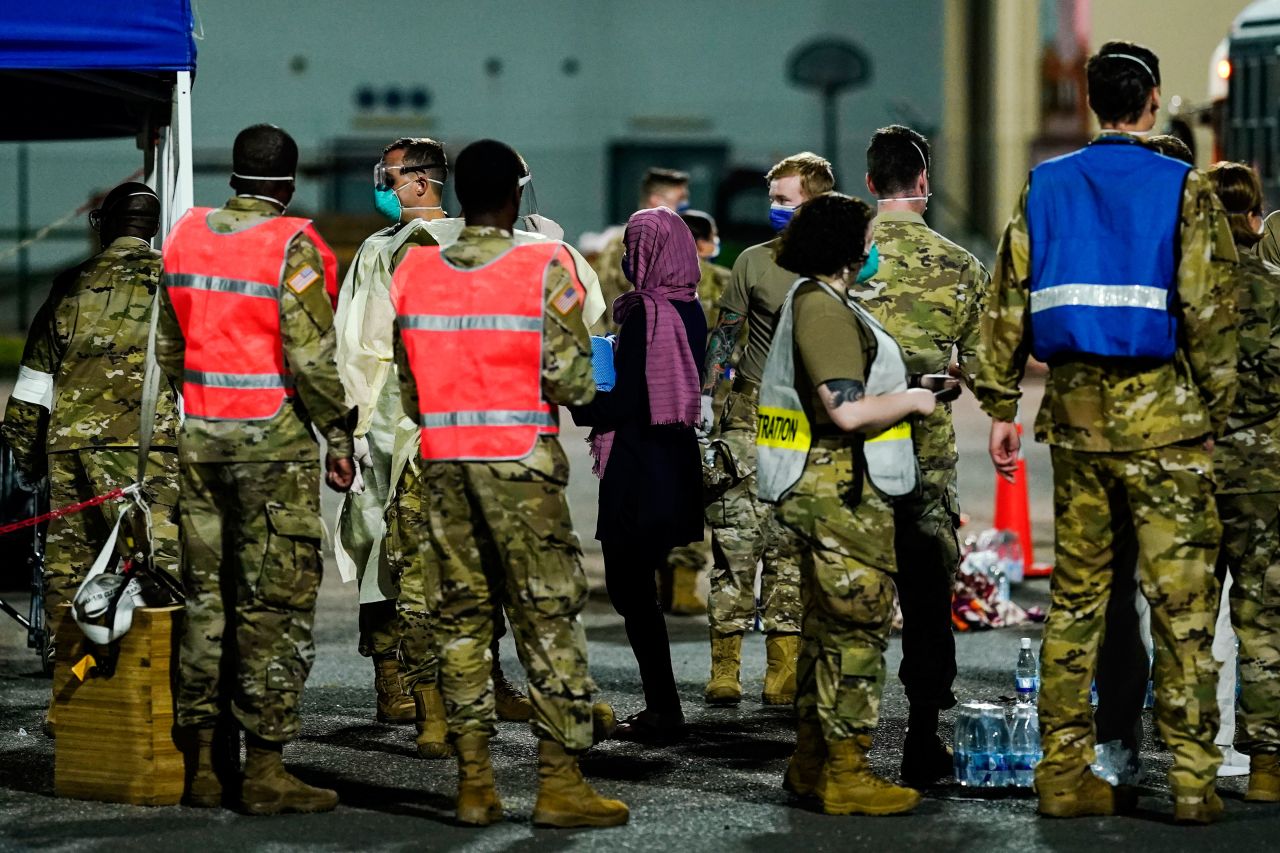 Soldiers and helpers stand as people evacuated from Afghanistan leave a transport bus at Ramstein Air Base in Germany on August 20, 2021.
