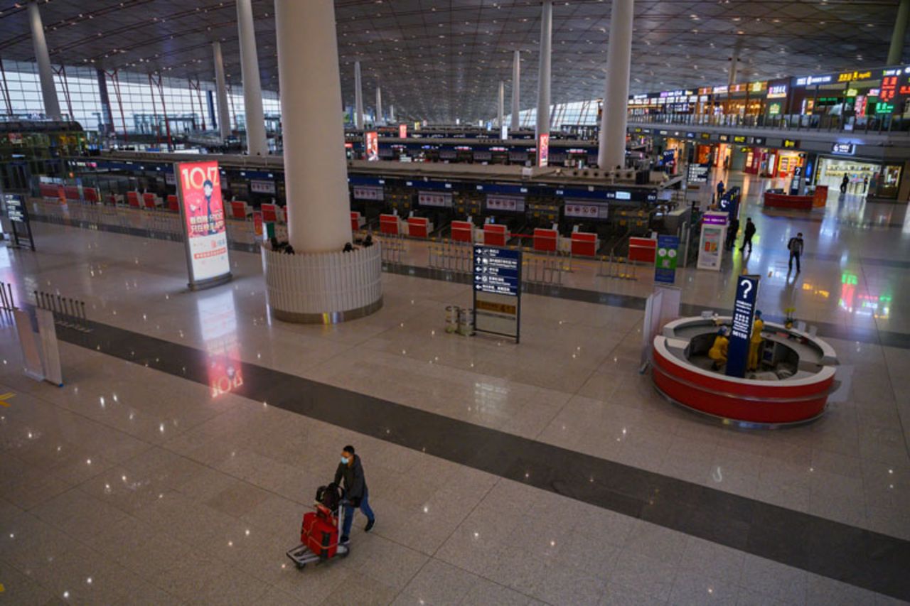 A Chinese man wears a protective mask as he pushes his luggage by closed check in counters in the departures area at Beijing Capital International Airport on March 24 in Beijing, China.