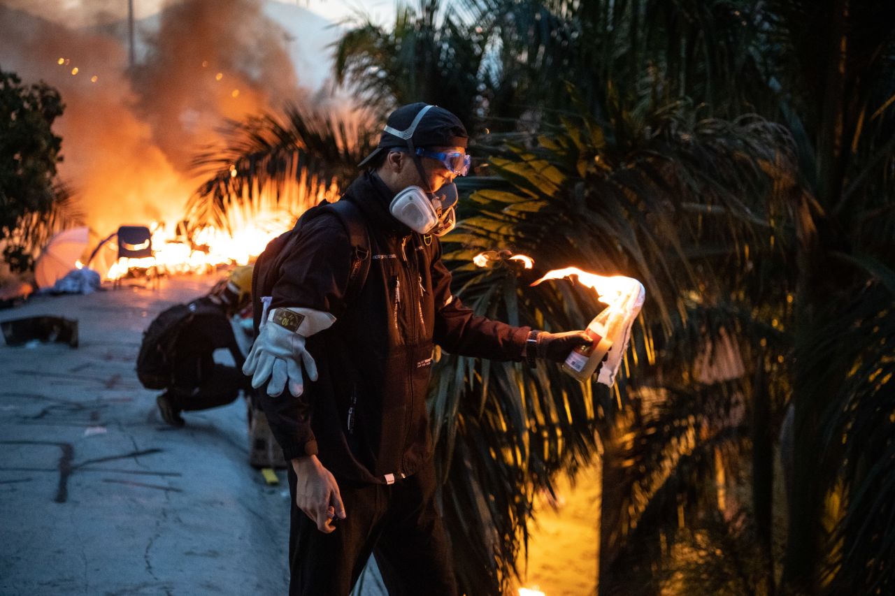 A protester lights a petrol bomb in front of a fire on a pedestrian bridge during clashes with police at Hong Kong Polytechnic University on November 18.