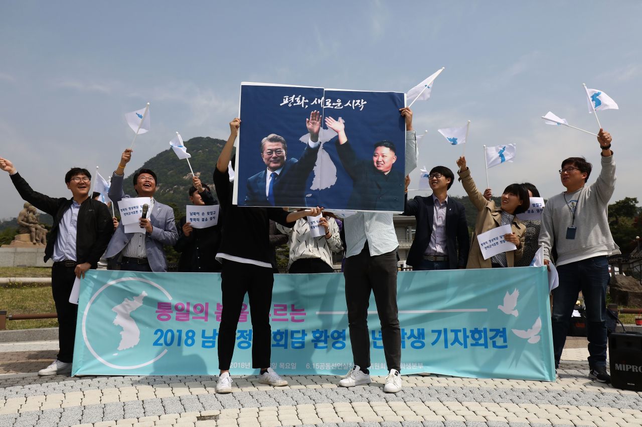 South Koreans hold up placards of Moon and Kim during a rally in front of the Presidential Blue House on Thursday in Seoul.