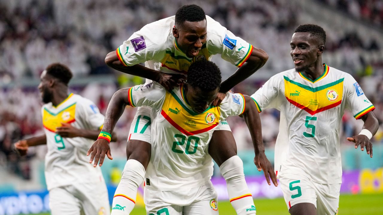Teammates celebrate with Senegal's Bamba Dieng (No. 20) after he scored the team's third goal against Qatar.