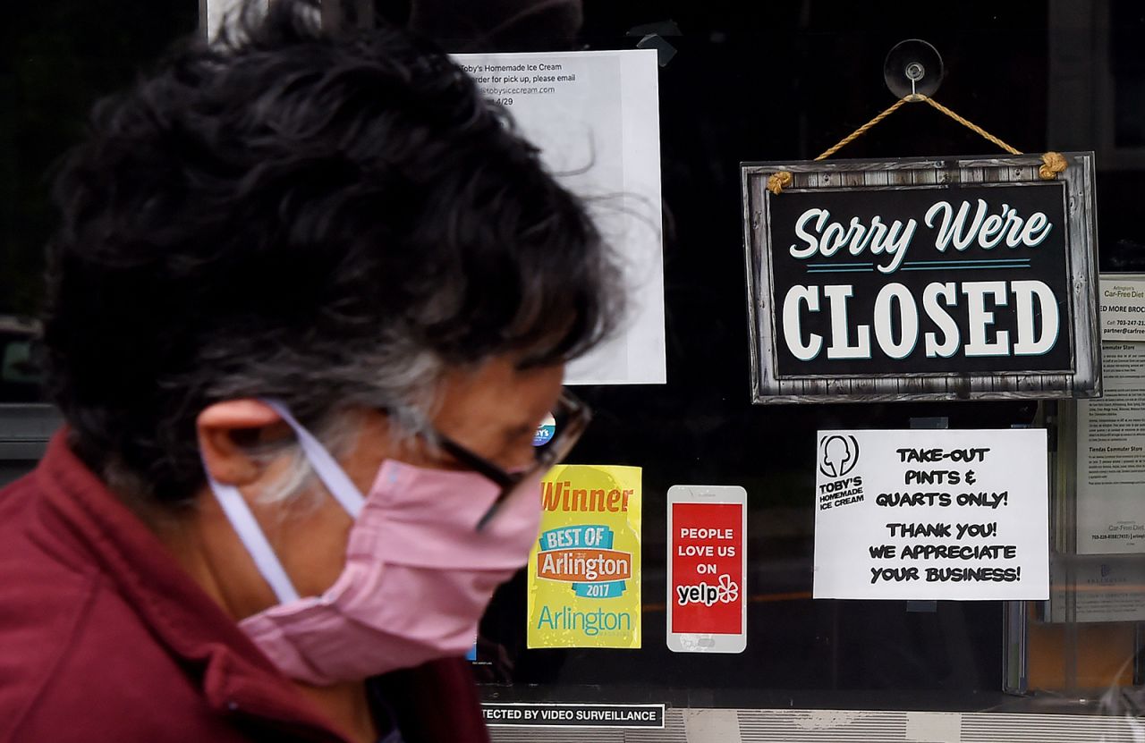 A person wearing a face mask walks past a sign in the window of an ice cream store in Arlington, Virginia on May 5.