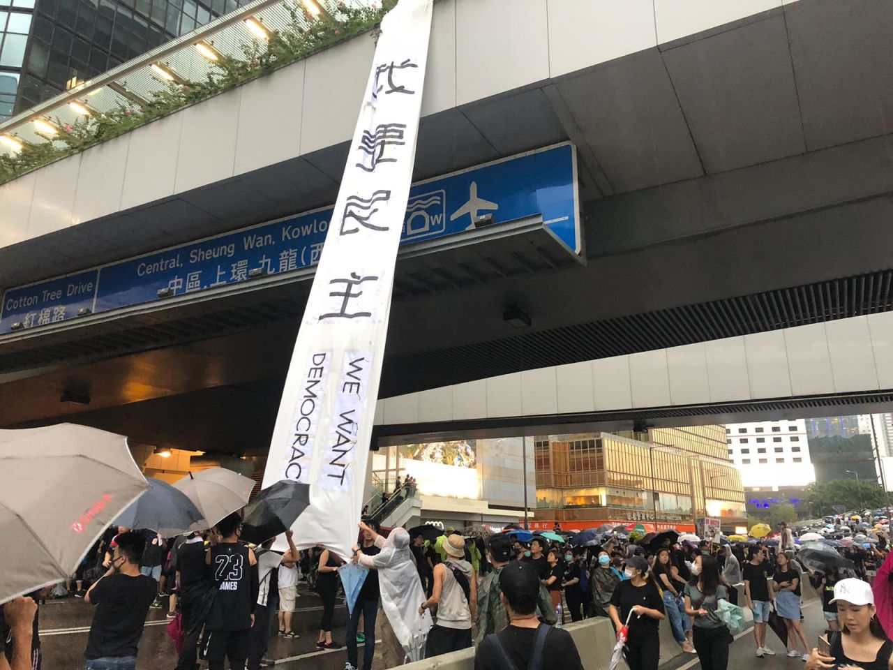 Protesters unfurl a banner reading "We want democracy" on Harcourt Road